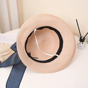 Detail of hollow woven straw hat with navy bow ribbon and elastic windproof strap