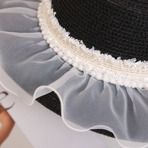 Detail of straw hat with white pearls, lace trim, and pleated organza mesh brim