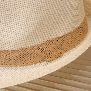 Detailed close-up of fine woven straw hat texture with dark brown decorative band