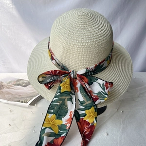 Détail d'un chapeau de paille à larges bords avec ruban floral et grand nœud décoratif