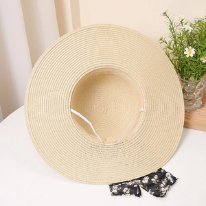 Detail of handwoven straw hat showing fine texture, inner wind rope and floral bow accessory
