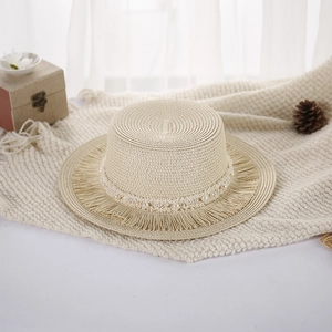 Dettaglio di cappello in paglia elegante con catena di perle e bordi a frange
