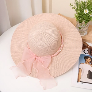 Detailansicht des rosa Strohhuts mit Chiffon-Schleife und eleganter Perlenverzierung