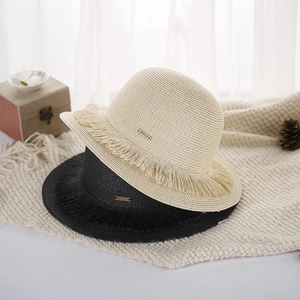 Chic straw sun hat with fringe brim and metal peace plate on a cozy woven blanket