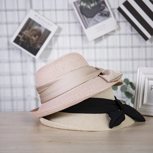 Close-up of woven sun hat with elegant silk ribbons in pink and champagne colors