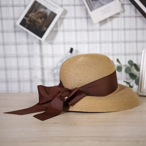 Detail of fine-woven straw hat with elegant brown grosgrain ribbon and bow decoration