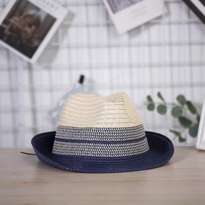 Detail of navy blue and cream woven straw fedora hat on a minimalist wooden table