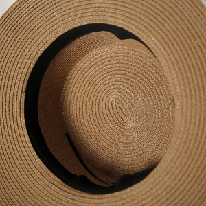 Vista dettagliata di un cappello di paglia stile boater con nastro nero e trama a spirale
