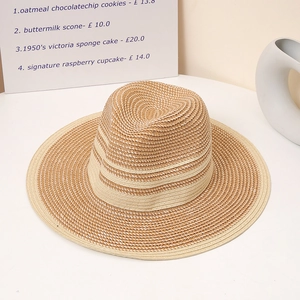 Close-up of beige and brown woven straw sun hat with decorative band on a minimalist table
