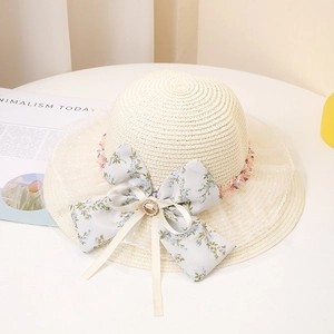 Détail du nœud floral et de la dentelle à pois sur le chapeau de paille tissé