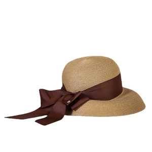 Handwoven straw sun hat with deep brown ribbon bow and elegant gold pendant detail