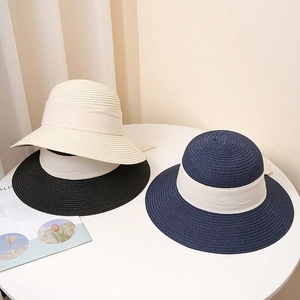 Detailed view of three woven sun hats in cream, black and navy with ribbon accents