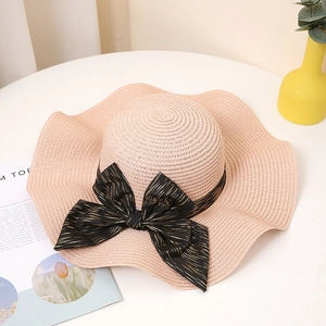 Détail d'un chapeau de paille à large bord avec nœud noir sur décor d'été minimaliste