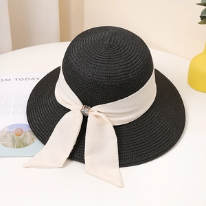 Detail of black straw hat with cream chiffon ribbon bow and decorative bead buckle