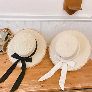 Detail of raffia flat top straw hats with frayed edges and elegant ribbon bows