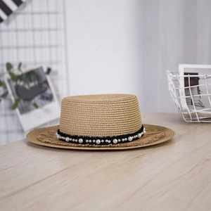Dettaglio cappello di paglia a tesa larga con perle eleganti e bordo con frange