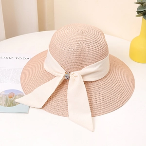 Detail of wide brim straw hat featuring a large satin bow and crystal buckle ornament