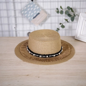Dettaglio del bordo a frange del cappello di paglia e nastro nero con perle applicate