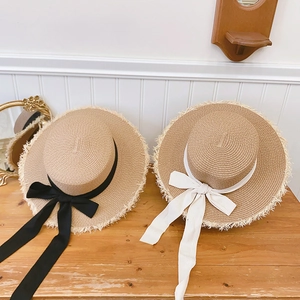 Close-up of raffia sun hats with frayed edges and elegant ribbon bows on wooden table
