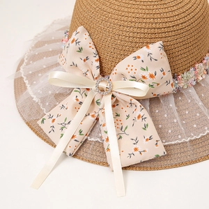Gros plan d'un nœud floral avec boucle en diamant et dentelle sur un chapeau de paille