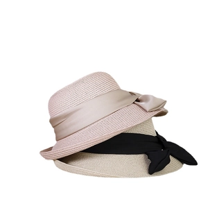 Flat lay of woven straw sun hats with satin bows in pink and beige colors