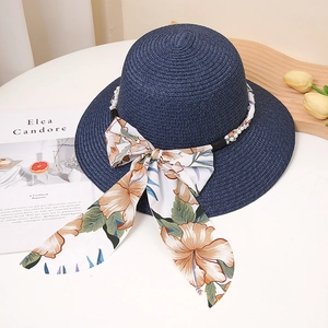Détail du chapeau de paille bleu marine avec perles et grand ruban à motif floral