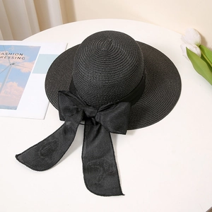 Detail of elegant black straw sun hat with decorative ribbon bow and French style setting