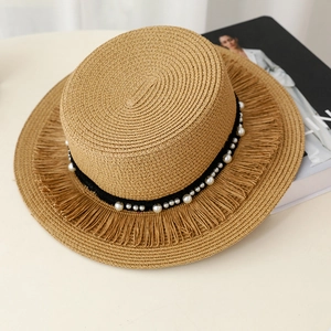 Dettaglio cappello di paglia con nastro di perle e tesa sfrangiata stile bohémien