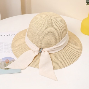 Close-up of wide-brimmed straw hat featuring ribbon tie and colorful gemstone buckle detail
