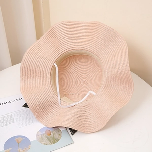 Détail du chapeau de soleil rose à bord ondulé avec texture tissée et cordelette
