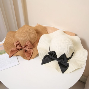 Straw sun hats for women with large ribbon bows in brown and cream wavy brim design
