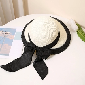 Close-up of the woven texture on a bicolor straw hat with an elegant black silk ribbon
