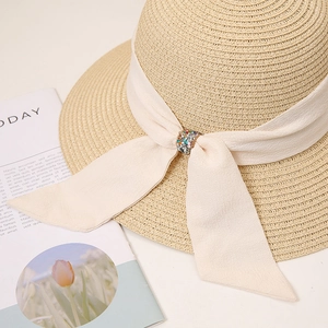 Detail of elegant straw hat with cream chiffon bow and crystal buckle embellishment