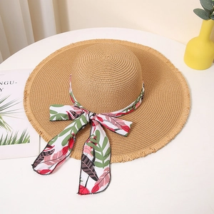 Close-up of a wide-brim straw hat with a tropical floral ribbon bow and frayed edges