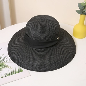 Détail de la texture en paille tressée et boucle dorée sur ce chapeau de soleil noir