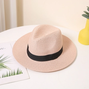 Rosa gewebter Strohhut mit schwarzem Band auf einem minimalistischen Display