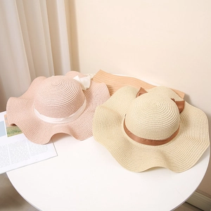 Women's straw sun hats with wavy brims and elegant ribbon bows for summer beach wear