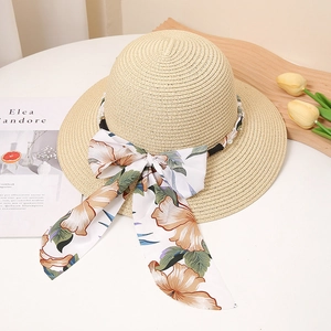 Détail du chapeau de paille avec ruban floral et perles sur un décor d'été chic