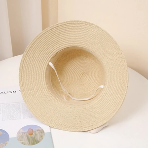 Detail of hand-woven straw sun hat showing interior sweatband and white elastic chin strap