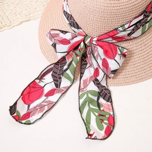 Detailed macro view of summer straw hat with floral ribbon bow on white lace