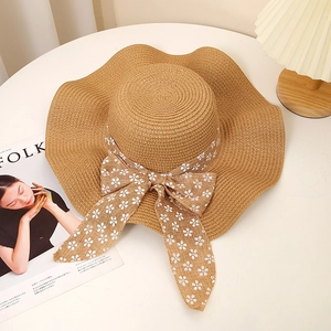 Close-up of wavy brim straw hat with floral ribbon on a white table with Kinfolk magazine
