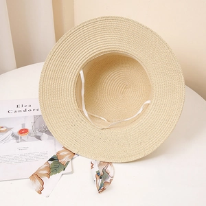 Détail d'un chapeau de paille beige avec ruban floral et cordon coupe-vent ajustable
