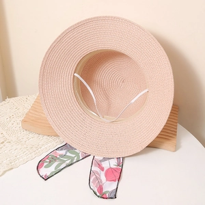 Detail of light pink straw sun hat showing floral ribbon bow and woven paper texture