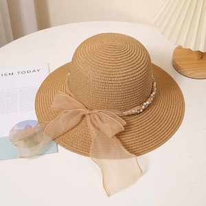 Détail d'un chapeau de paille d'été avec ruban de perles et nœud en organza pour femme