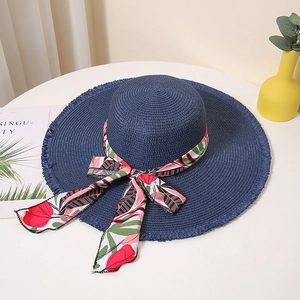 Close-up of deep blue straw hat featuring tropical floral ribbon and frayed wide brim