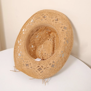 Vue détaillée du tissage floral ajouré sur un chapeau de paille kaki avec bande de sudation