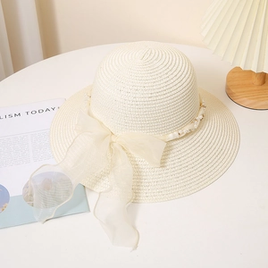 Détail d'un chapeau de paille beige avec un nœud en tulle et des perles élégantes