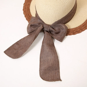 Detail of the woven straw hat showing the two-tone contrast and stylish bow knot decor