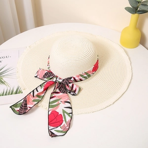 Detailed shot of summer straw hat with floral ribbon bow on white tabletop scene