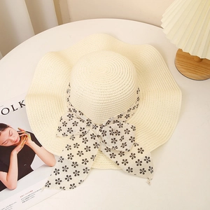 Detail of summer straw hat with lace floral ribbon bow on white table setting